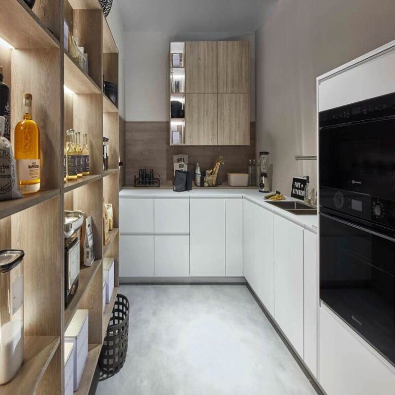 Moderne weiße Küche mit Hochschränken, Holzregal und schwarzen Einbaugeräten – Einbauküche